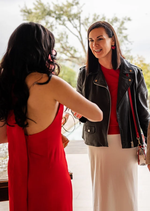A guest in a black jacket smiling during a greeting