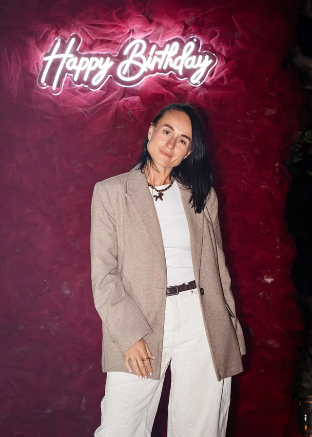 An evening portrait in front of the glowing birthday sign and red backdrop