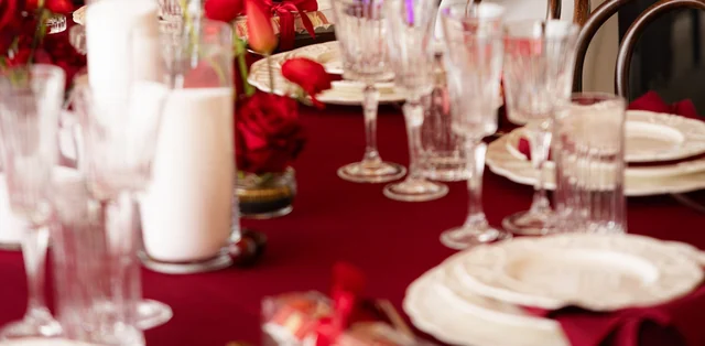 A close view of candles, red flowers and glasses on the birthday table