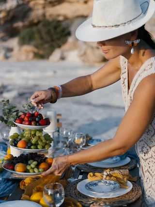 A woman arranging a tiered fruit stand on a seaside table