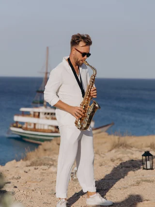 A saxophonist in white beside the sea