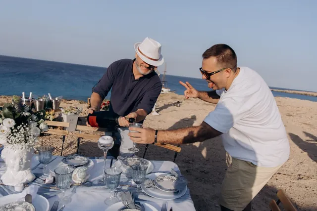 Guests opening a bottle beside the seaside picnic table
