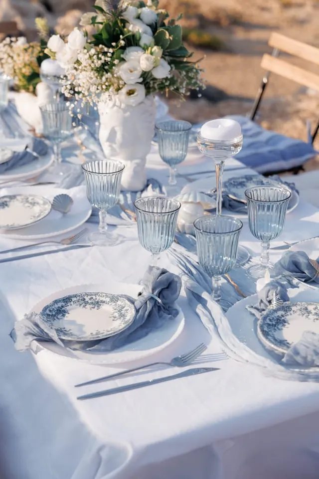 White flowers, blue plates and pale-blue glasses on the anniversary table