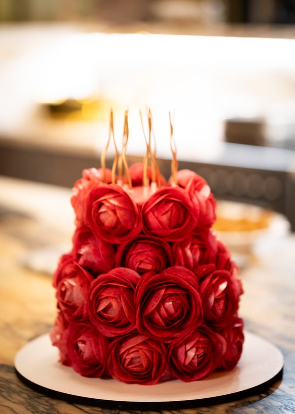 A cake decorated with red icing roses and long candles