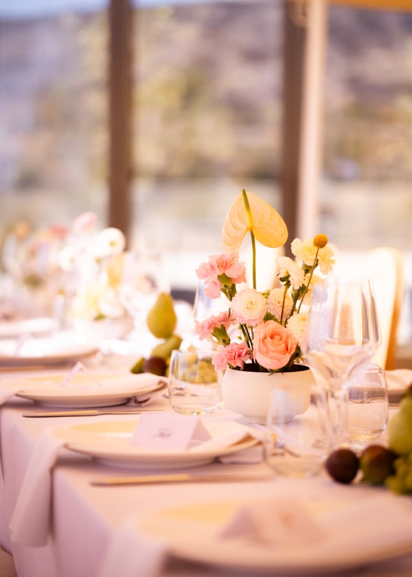 A pale pink table setting with flowers and fruit