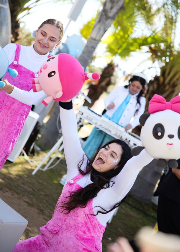 Entertainers in pink outfits holding colourful character toys