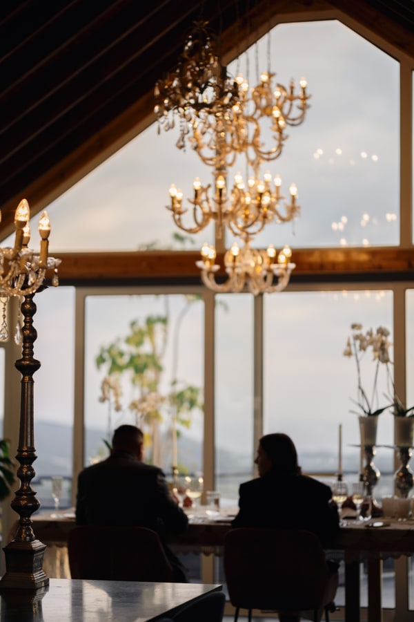A couple at a candlelit table beside large windows