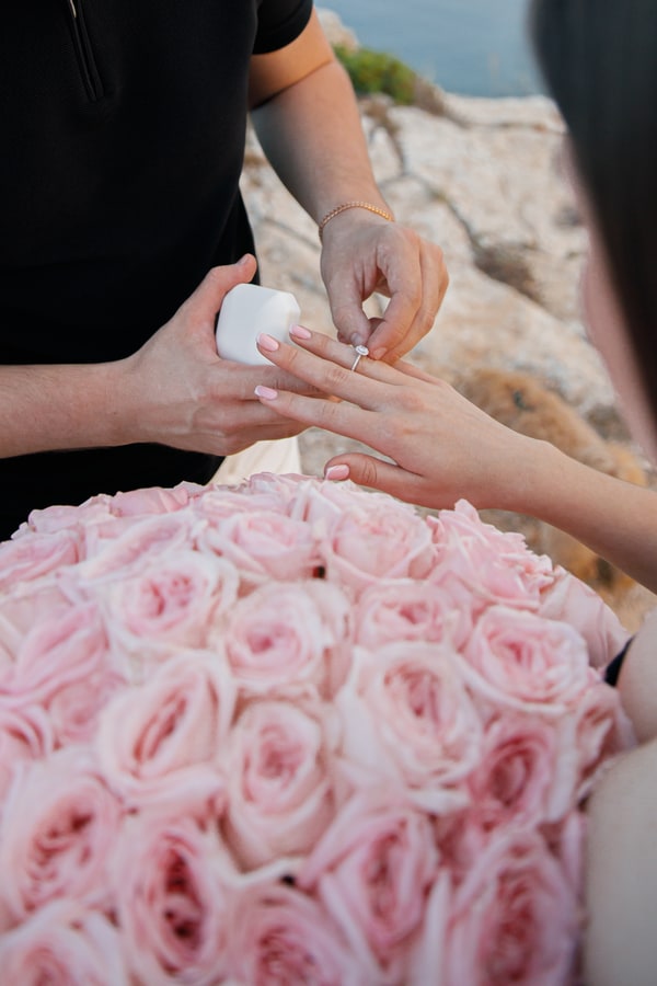 The couple looking at the engagement ring beside the roses