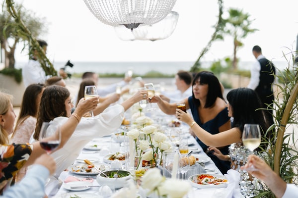 Wedding guests raising their glasses across the long reception table