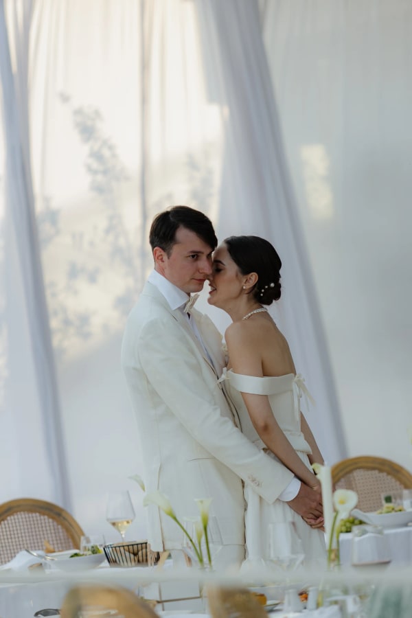 Lesya and Nikita sharing a quiet moment beside softly lit white curtains