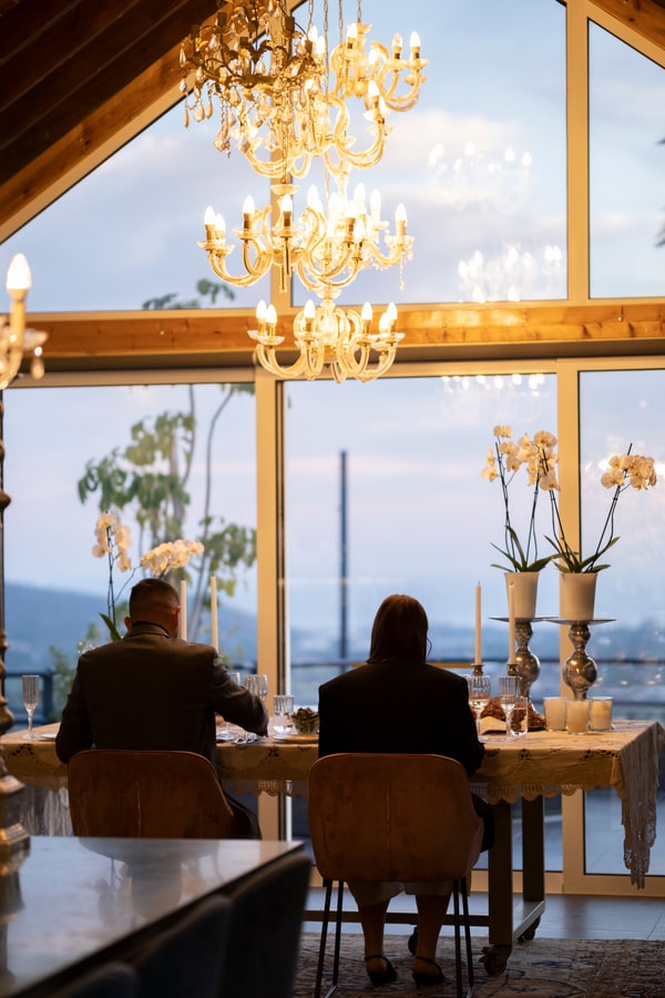 A couple at a candlelit table beside large windows