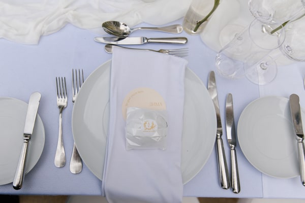 White plates, a folded napkin and silver-coloured cutlery at a wedding place setting
