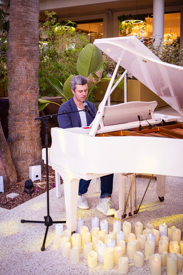 A pianist beside a white grand piano by the pool