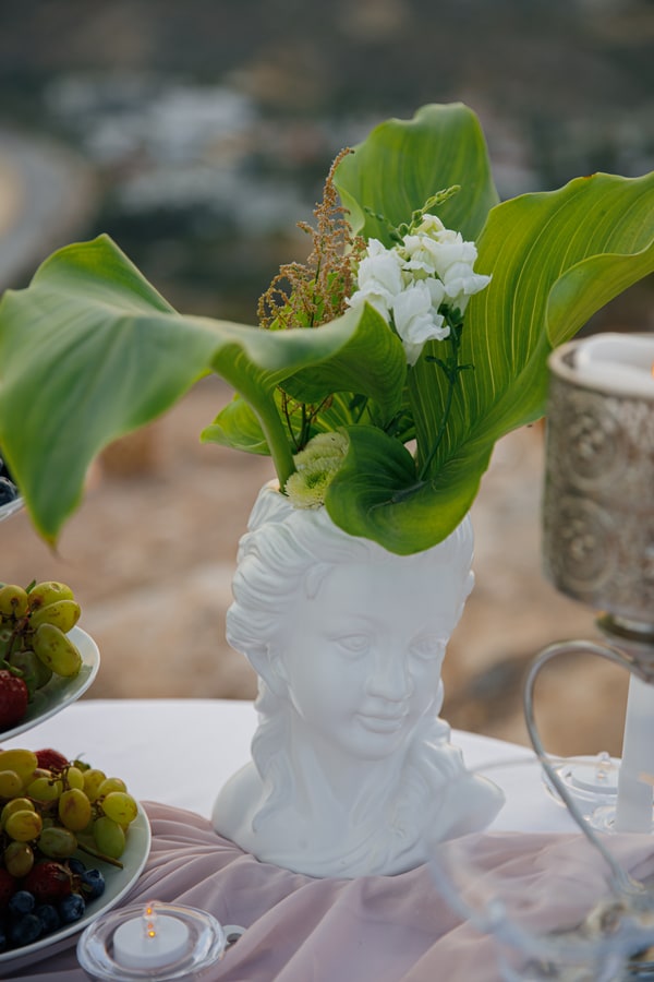 Green and white flowers in a sculpted vase