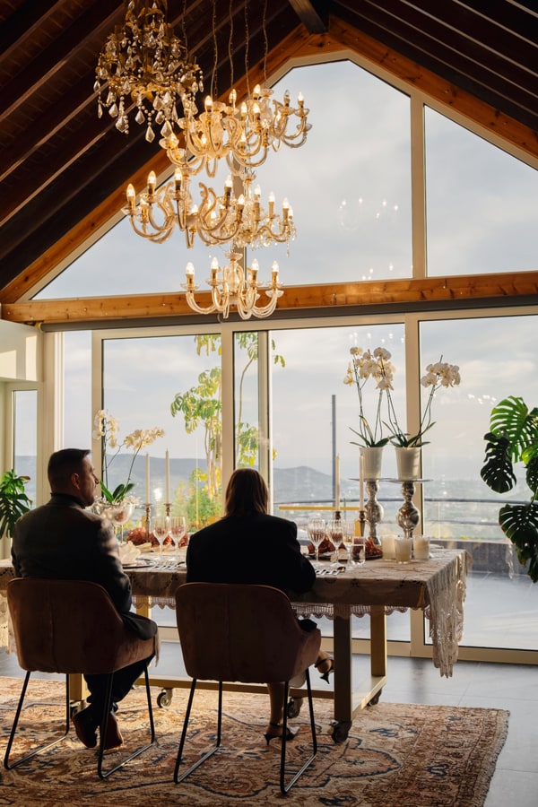 A couple at a candlelit table beside large windows