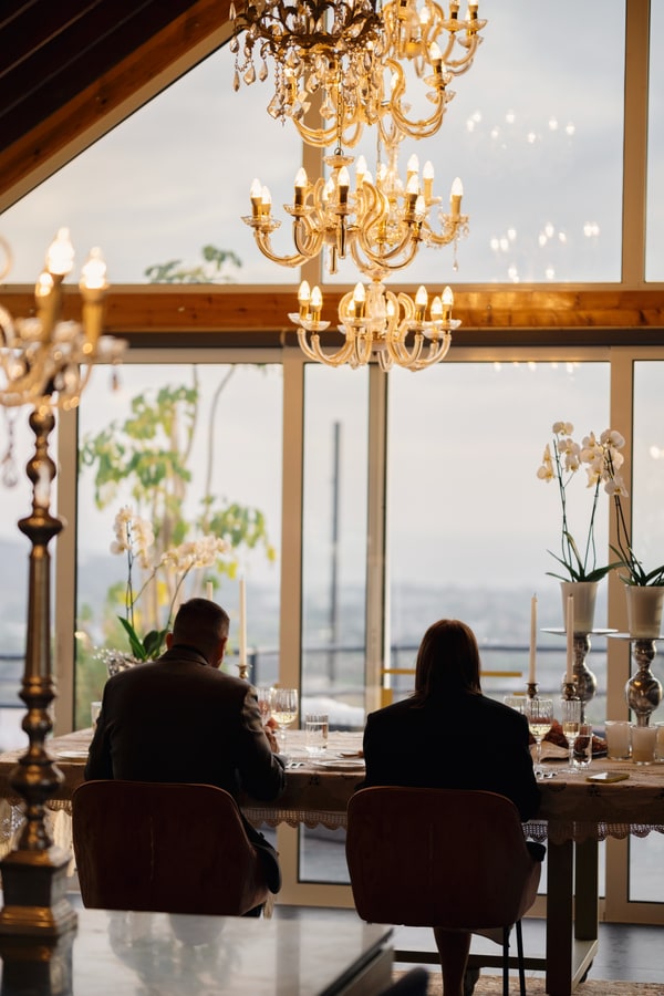 A couple at a candlelit table beside large windows