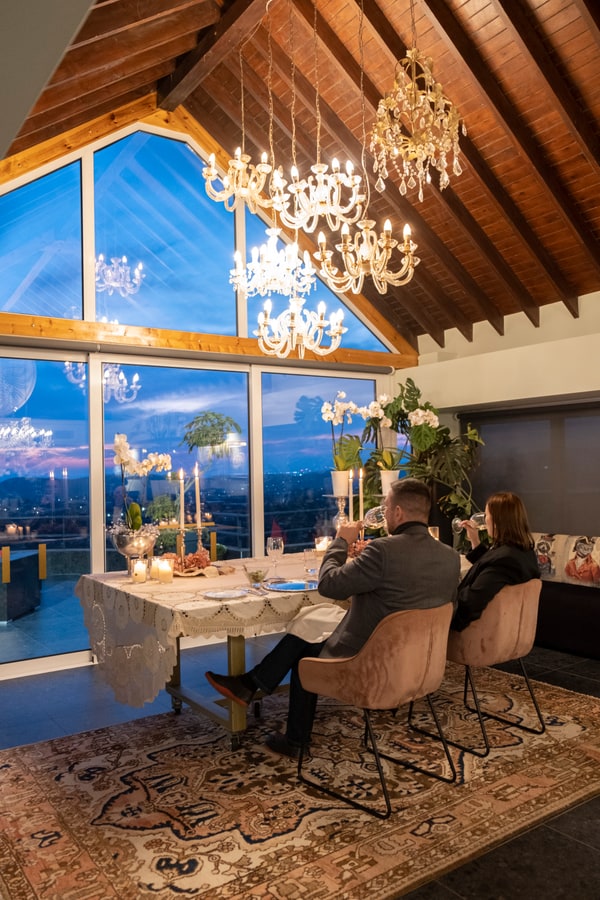 A couple at a candlelit table beside large windows
