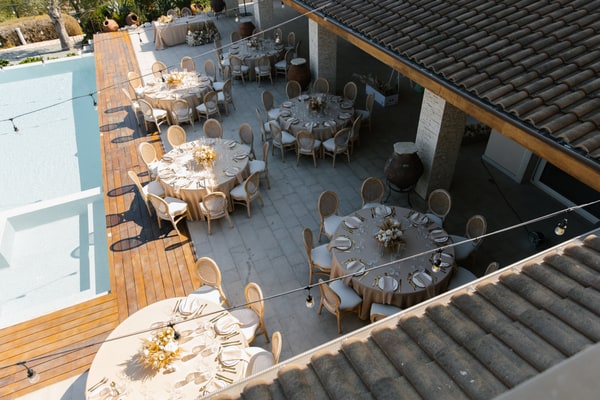 Reception tables and woven chairs arranged beside a swimming pool