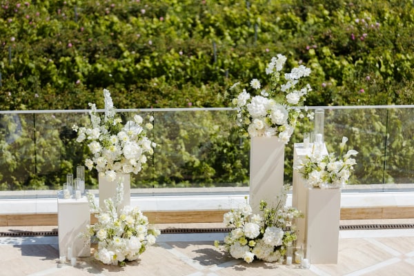 White flower arrangements and candles framing the outdoor ceremony space