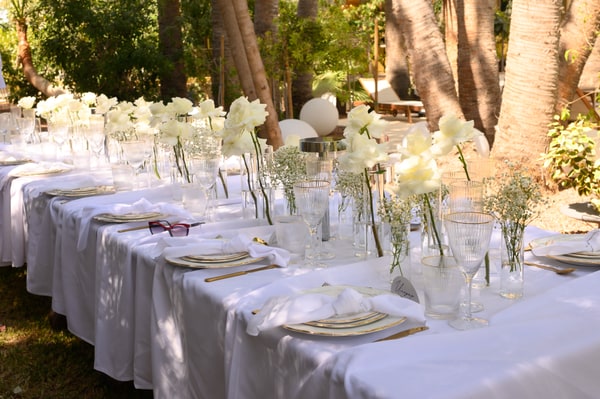 A long white wedding table with flowers in the garden