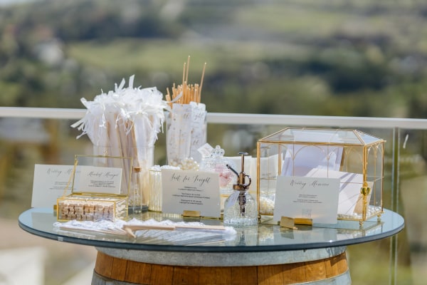 Wedding stationery and glass boxes arranged on a barrel table overlooking the hills