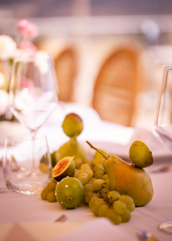 A pale pink table setting with flowers and fruit