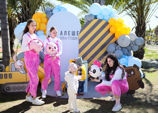 Entertainers in pink outfits holding colourful character toys