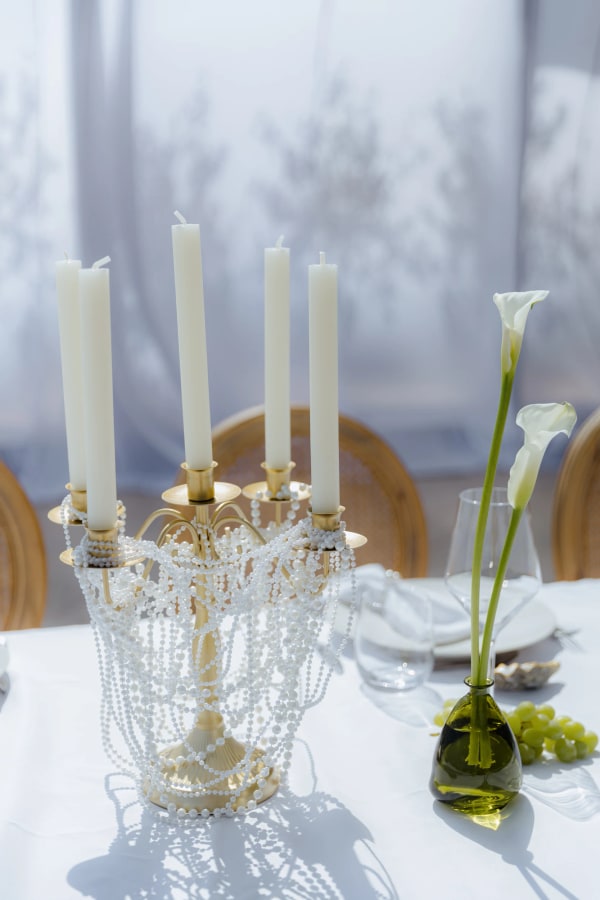 White candles, clear glassware and a white calla lily on the table