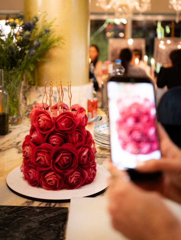 A cake decorated with red icing roses and long candles