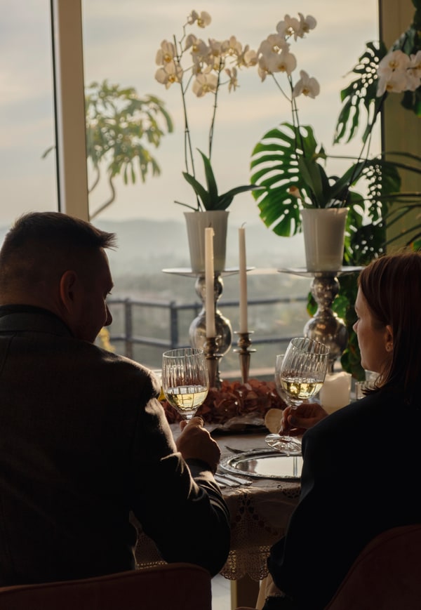 A couple at a candlelit table beside large windows