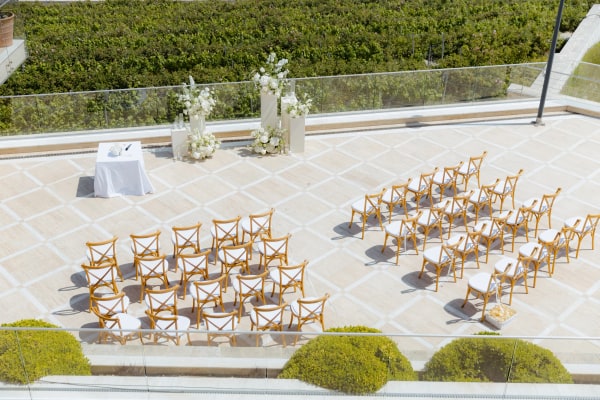 Rows of wooden chairs facing white ceremony flowers on a winery terrace
