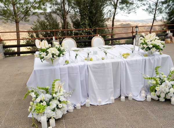 White flowers cascading beside a long reception table draped in soft fabric