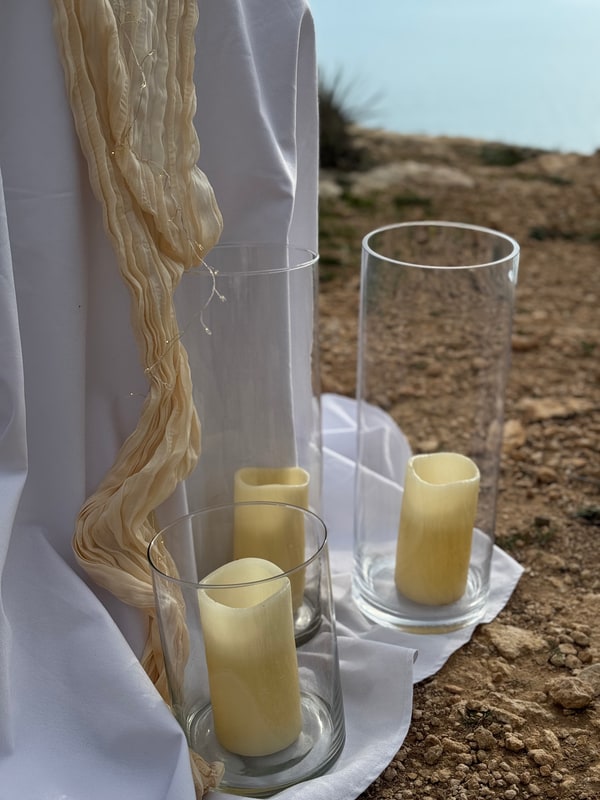 A seaside picnic table with teacups, pale fabric and candles