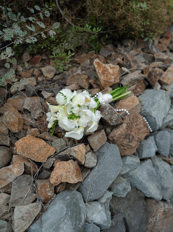 A white bridal bouquet resting on a rustic stone wall
