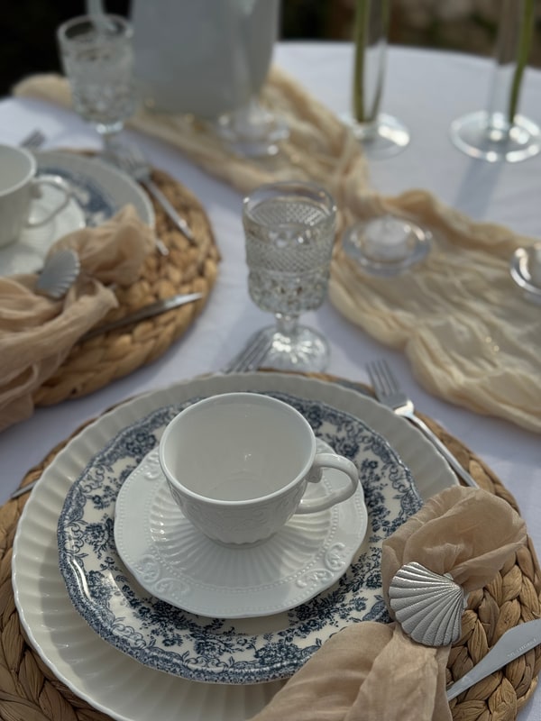 A seaside picnic table with teacups, pale fabric and candles