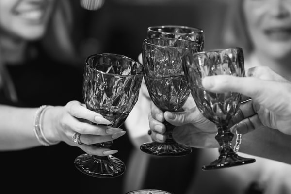 Guests holding cut-glass tumblers for a toast