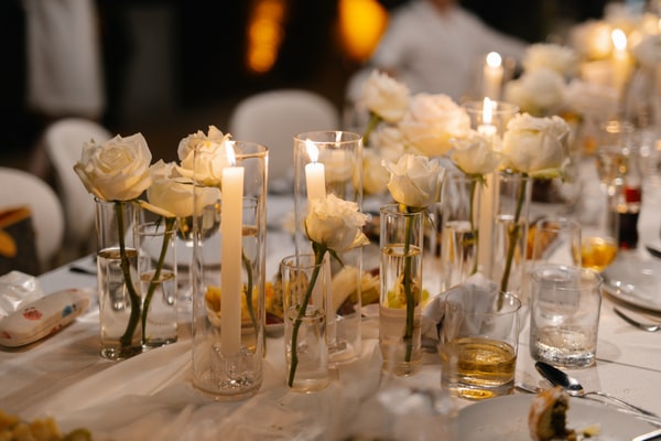White roses in glass vases and candlelight on the evening reception table