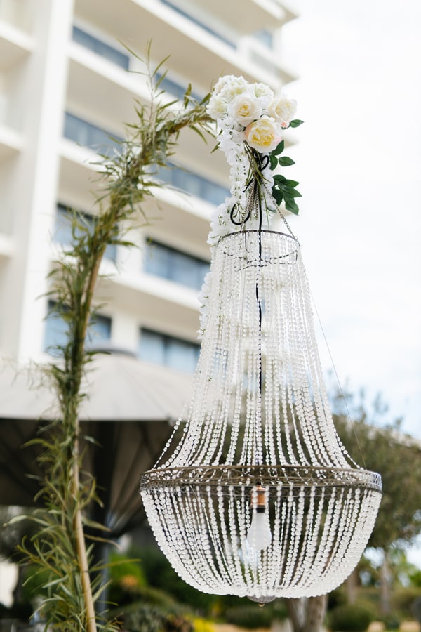 A crystal chandelier hanging from a curved floral frame