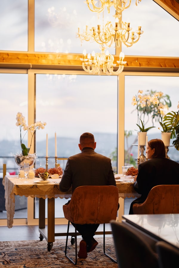 A couple at a candlelit table beside large windows