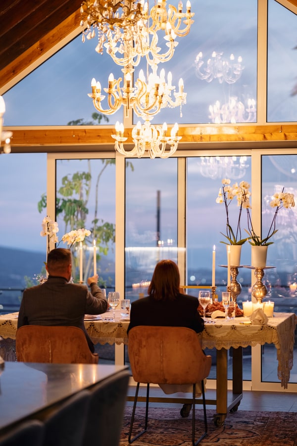 A couple at a candlelit table beside large windows