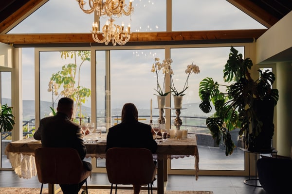 A couple at a candlelit table beside large windows
