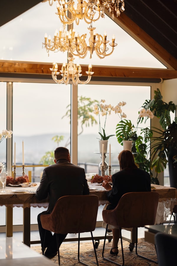 A couple at a candlelit table beside large windows
