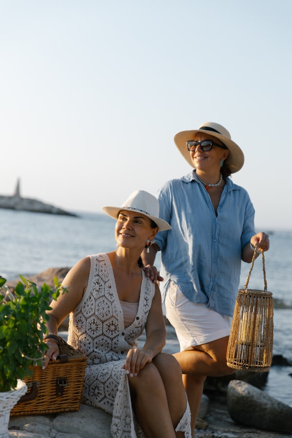 Two women in hats beside the seaside picnic table