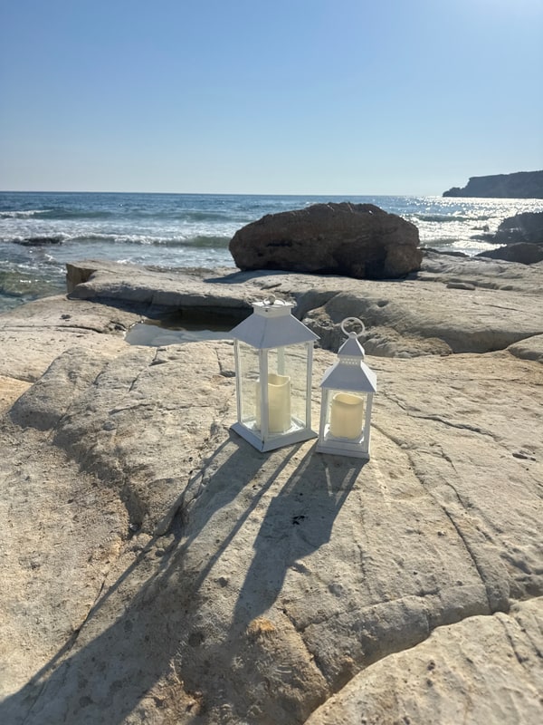 Two white lanterns on rocks beside the sea