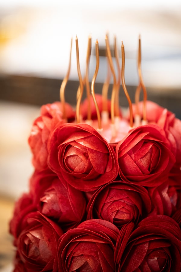 A cake decorated with red icing roses and long candles