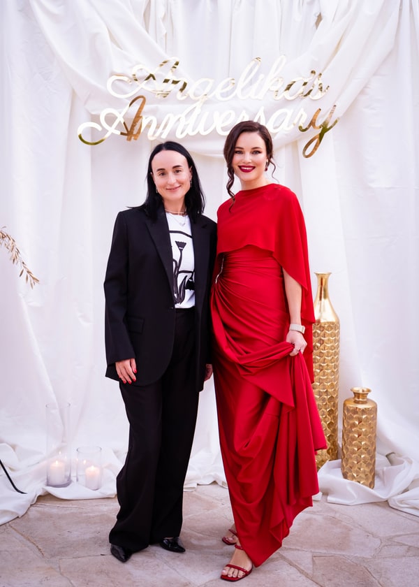 Two women posing beside the anniversary backdrop