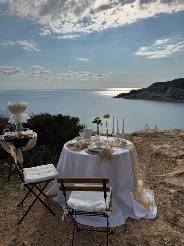 A seaside picnic table with teacups, pale fabric and candles