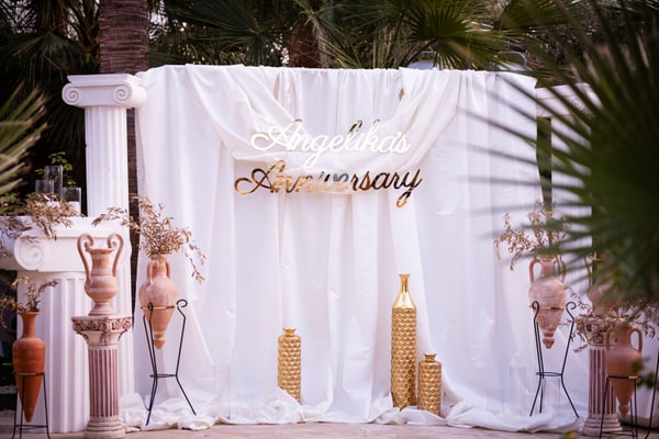 A draped anniversary backdrop with columns and decorative vases