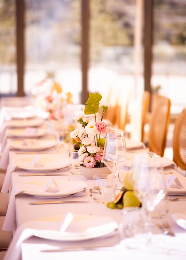A pale pink table setting with flowers and fruit