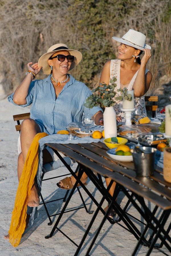 Two women in hats beside the seaside picnic table